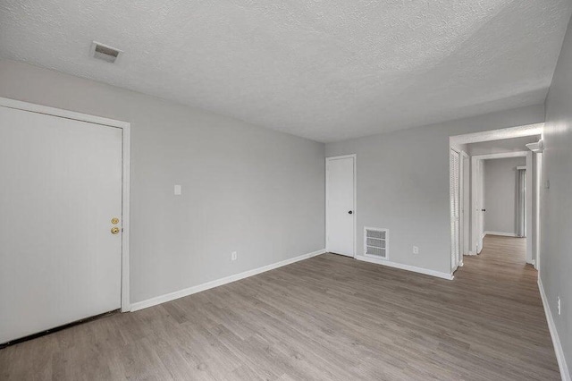 empty room with hardwood / wood-style flooring and a textured ceiling