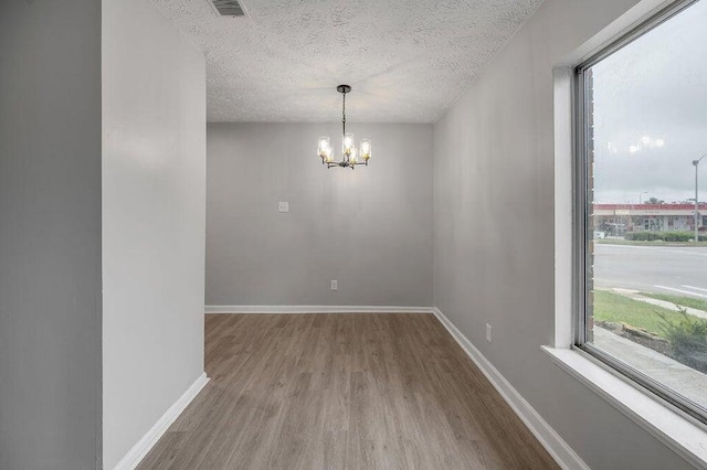 spare room featuring hardwood / wood-style floors, a textured ceiling, and a notable chandelier