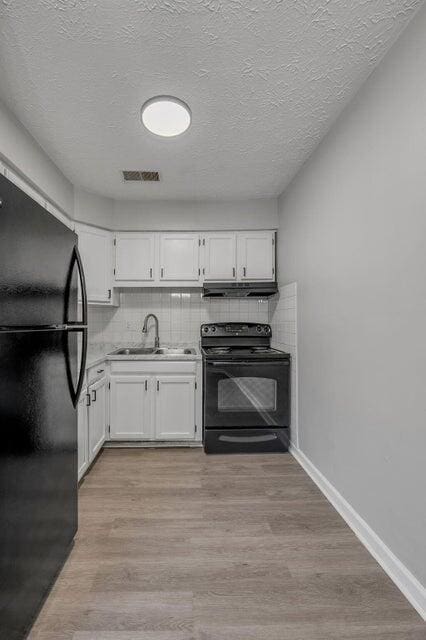 kitchen with backsplash, black appliances, white cabinets, sink, and light hardwood / wood-style floors