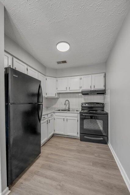 kitchen with white cabinetry, sink, decorative backsplash, black appliances, and light wood-type flooring