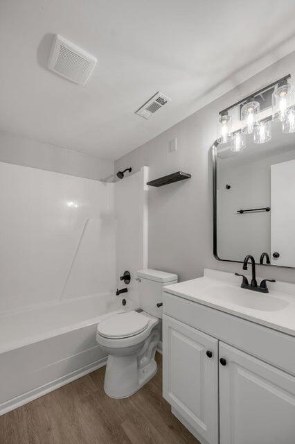 full bathroom featuring toilet, shower / washtub combination, vanity, and hardwood / wood-style flooring