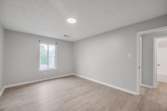 spare room featuring a textured ceiling and light wood-type flooring