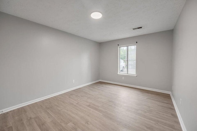 unfurnished room with a textured ceiling and light hardwood / wood-style flooring