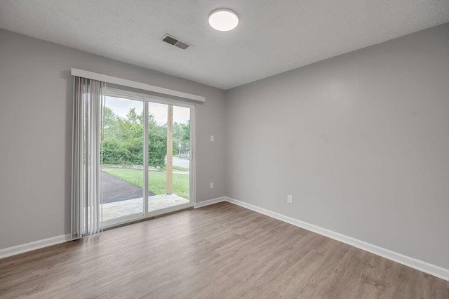 empty room with wood-type flooring and a textured ceiling