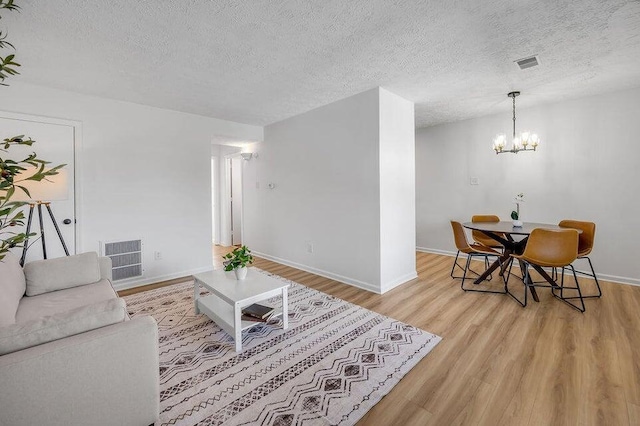 living room featuring a chandelier, a textured ceiling, and light wood-type flooring