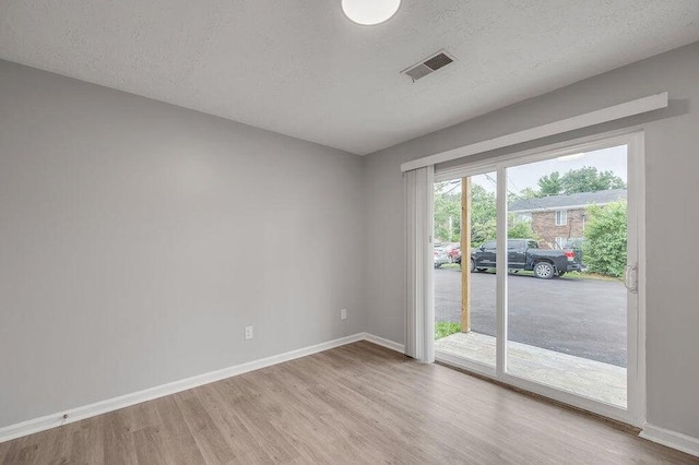 unfurnished room featuring light wood-type flooring and a textured ceiling