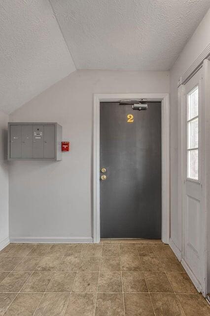 foyer entrance featuring a textured ceiling, mail boxes, and lofted ceiling