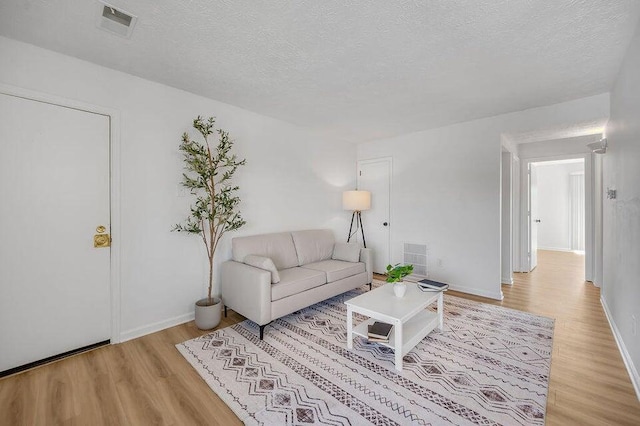 living room featuring a textured ceiling and light hardwood / wood-style flooring