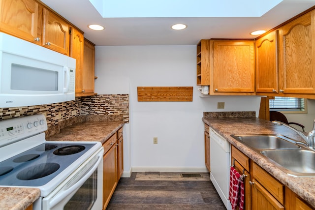 kitchen with a skylight, backsplash, dark hardwood / wood-style floors, white appliances, and sink