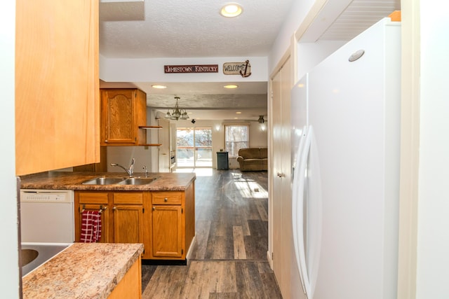 kitchen with dark hardwood / wood-style floors, a notable chandelier, sink, white appliances, and a textured ceiling