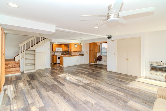 unfurnished living room with ceiling fan, heating unit, and hardwood / wood-style flooring