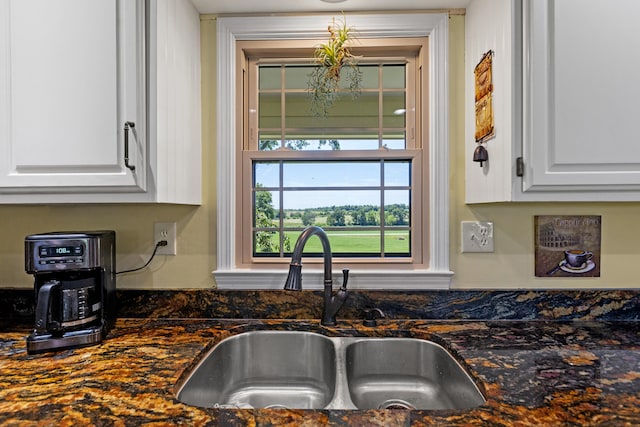 kitchen with white cabinets, dark stone countertops, and sink