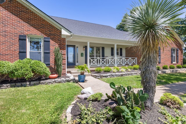 view of exterior entry with a lawn and a porch