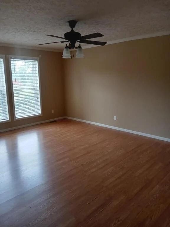 empty room with hardwood / wood-style floors, a textured ceiling, ceiling fan, and crown molding