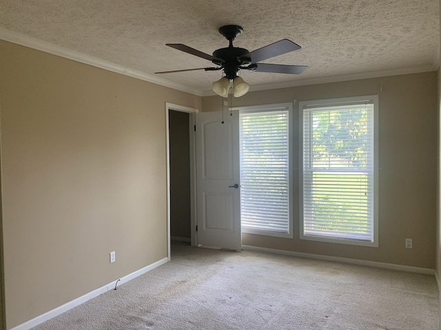 carpeted spare room featuring a textured ceiling, ceiling fan, and crown molding