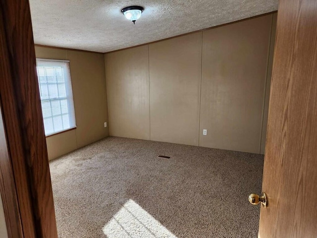 carpeted empty room featuring a textured ceiling