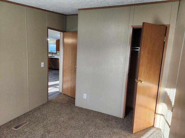 unfurnished bedroom featuring a textured ceiling, light colored carpet, a closet, and sink