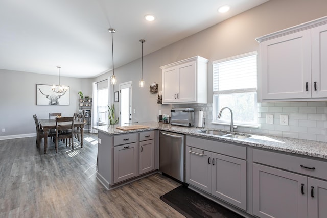 kitchen featuring sink, stainless steel dishwasher, kitchen peninsula, a chandelier, and decorative light fixtures