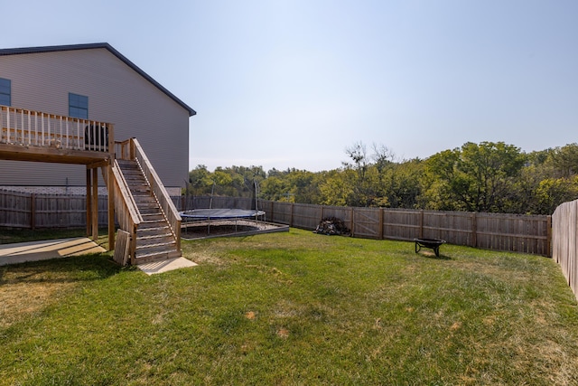 view of yard featuring a trampoline and a wooden deck