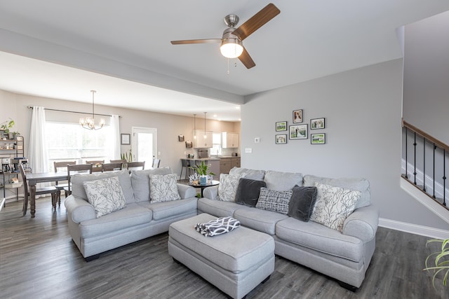 living room featuring ceiling fan with notable chandelier and dark hardwood / wood-style flooring