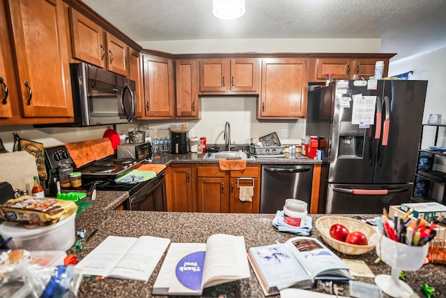 kitchen featuring sink, a textured ceiling, dark stone countertops, and appliances with stainless steel finishes