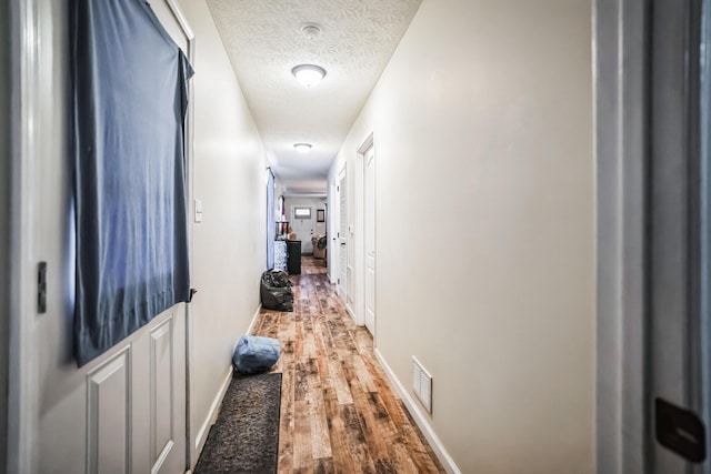 hall with a textured ceiling and hardwood / wood-style floors