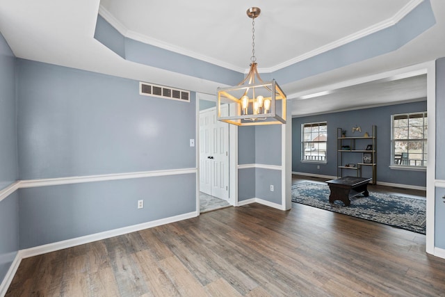 unfurnished dining area with a chandelier, dark hardwood / wood-style floors, a raised ceiling, and crown molding