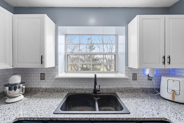 kitchen featuring white cabinetry, light stone countertops, sink, and decorative backsplash