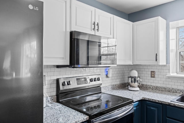 kitchen with blue cabinets, white cabinets, backsplash, light stone counters, and stainless steel appliances