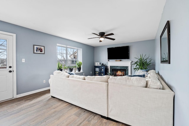 living room featuring hardwood / wood-style flooring, a premium fireplace, and ceiling fan