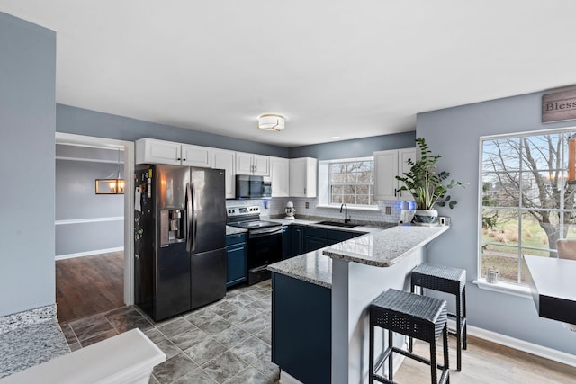 kitchen with refrigerator with ice dispenser, sink, a breakfast bar, white cabinetry, and range with electric cooktop