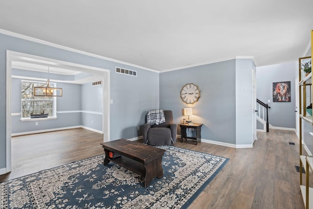 living area featuring hardwood / wood-style floors, crown molding, and a chandelier