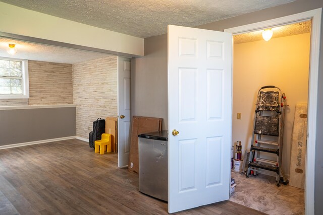 unfurnished bedroom with stainless steel fridge, a textured ceiling, a closet, and hardwood / wood-style floors