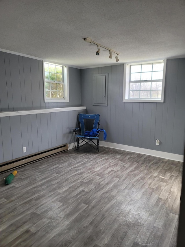 interior space featuring wood walls, rail lighting, a textured ceiling, and light wood-type flooring