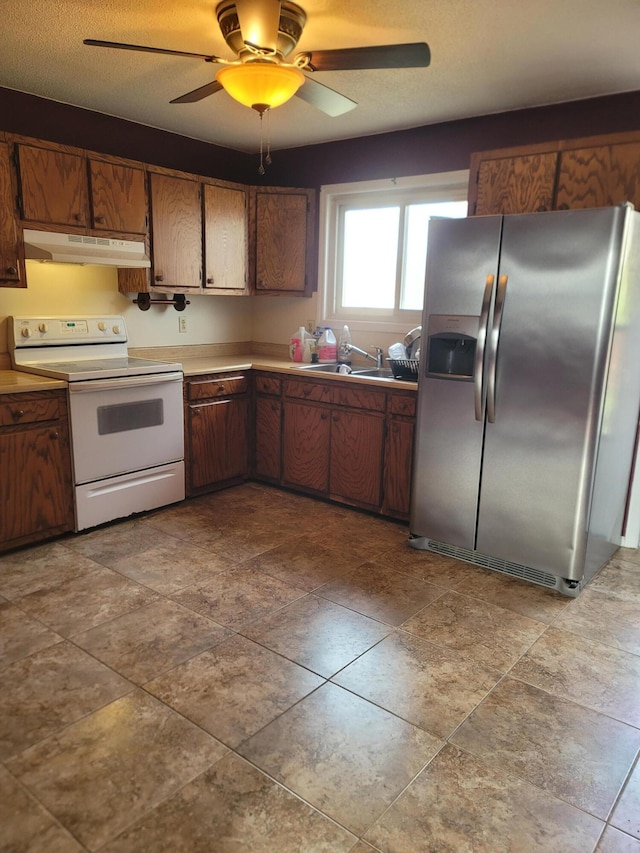 kitchen with stainless steel fridge, a textured ceiling, ceiling fan, sink, and electric stove