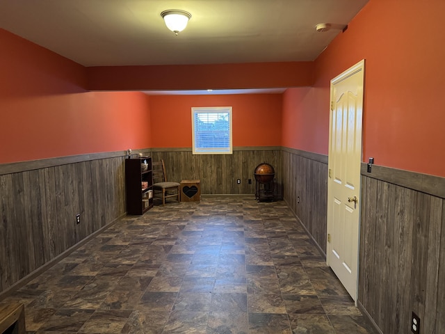 spare room with stone finish flooring and a wainscoted wall