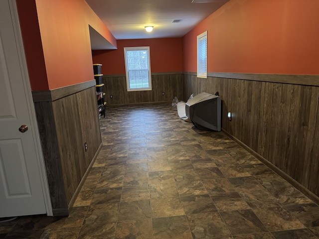 interior space featuring stone finish floor, a wainscoted wall, and visible vents