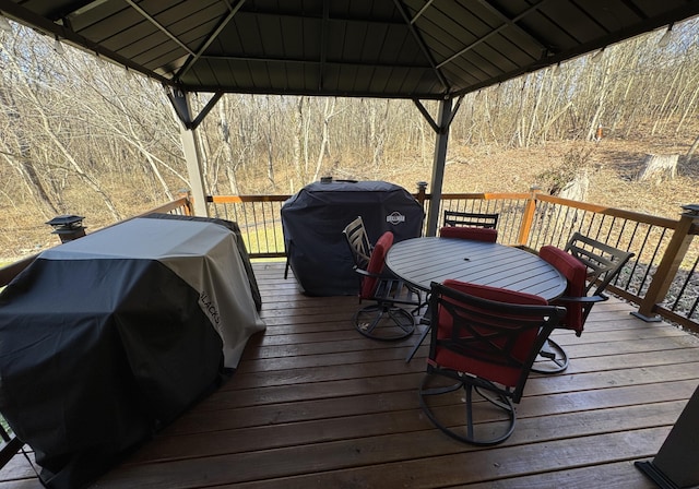 wooden deck featuring outdoor dining area, a grill, and a gazebo