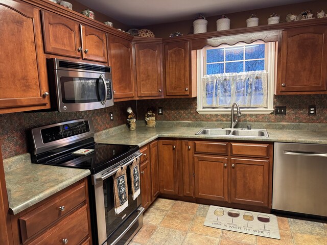 kitchen with tasteful backsplash, stainless steel appliances, a sink, and light countertops