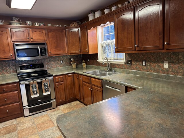 kitchen with stone finish flooring, appliances with stainless steel finishes, backsplash, and a sink