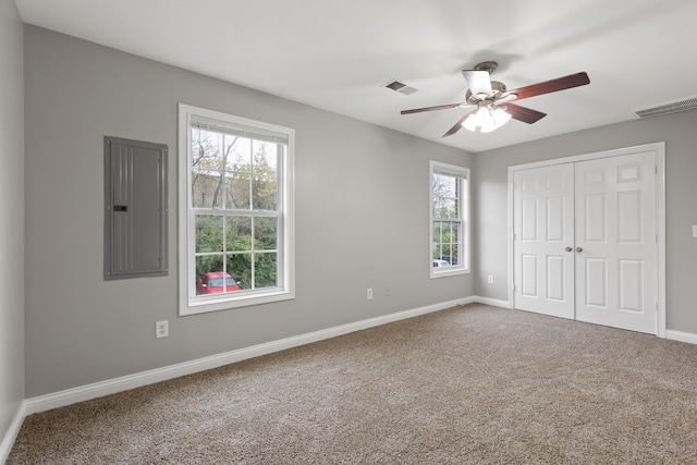 unfurnished bedroom featuring ceiling fan, multiple windows, electric panel, and a closet