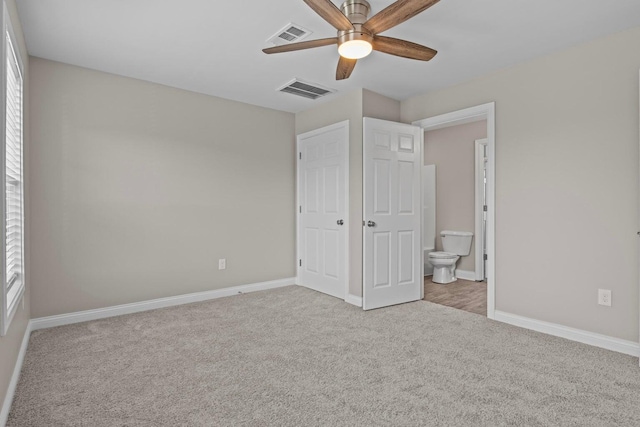 unfurnished bedroom featuring ceiling fan, light carpet, and ensuite bath