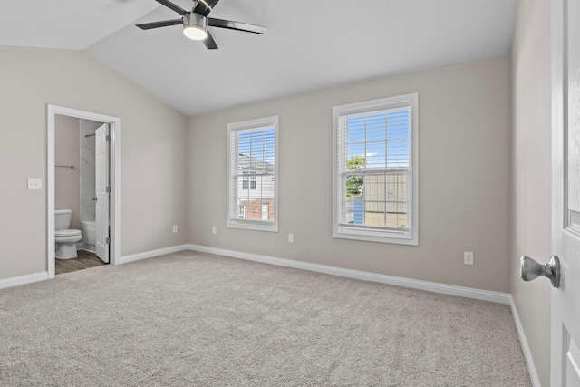 unfurnished bedroom with carpet, lofted ceiling, ensuite bathroom, a walk in closet, and ceiling fan