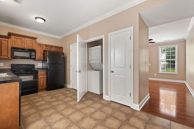 kitchen with tile patterned floors, crown molding, stacked washer and dryer, and black appliances