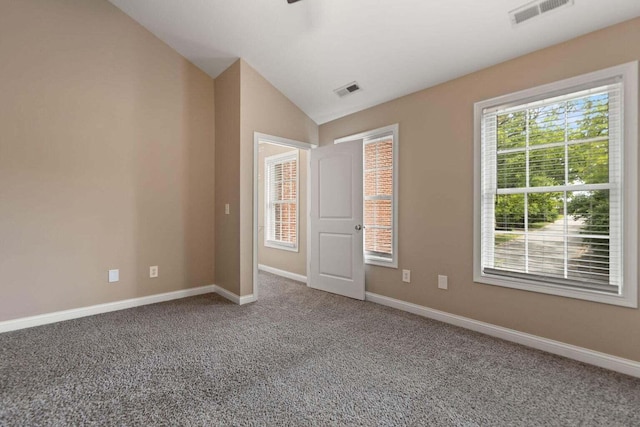 carpeted spare room featuring vaulted ceiling