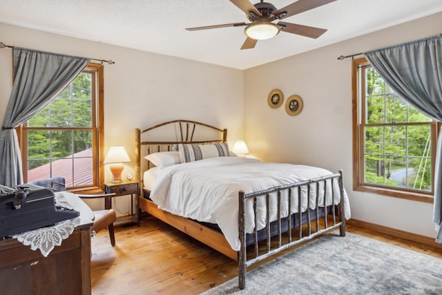 bedroom featuring ceiling fan, light wood-type flooring, and multiple windows