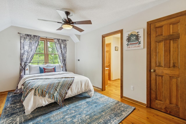 bedroom featuring ceiling fan, light hardwood / wood-style floors, a textured ceiling, and vaulted ceiling