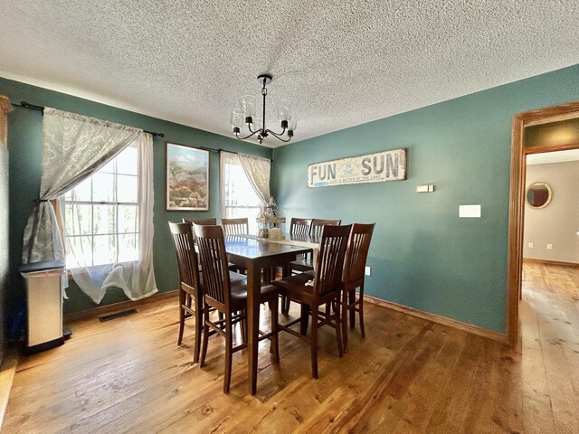 dining area featuring wood-type flooring, a textured ceiling, and a chandelier