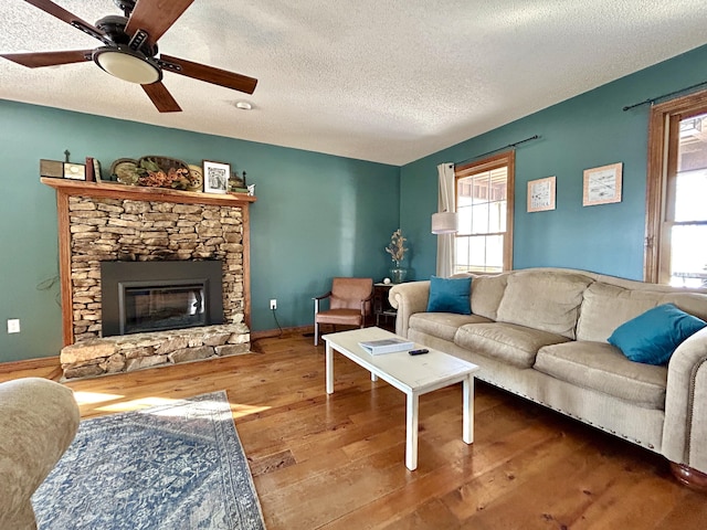 living room featuring a textured ceiling, ceiling fan, a fireplace, and hardwood / wood-style floors