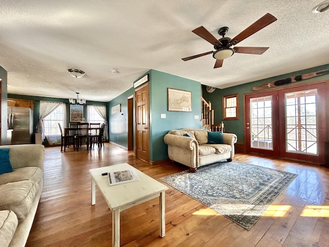 living room with ceiling fan with notable chandelier, a textured ceiling, and hardwood / wood-style flooring